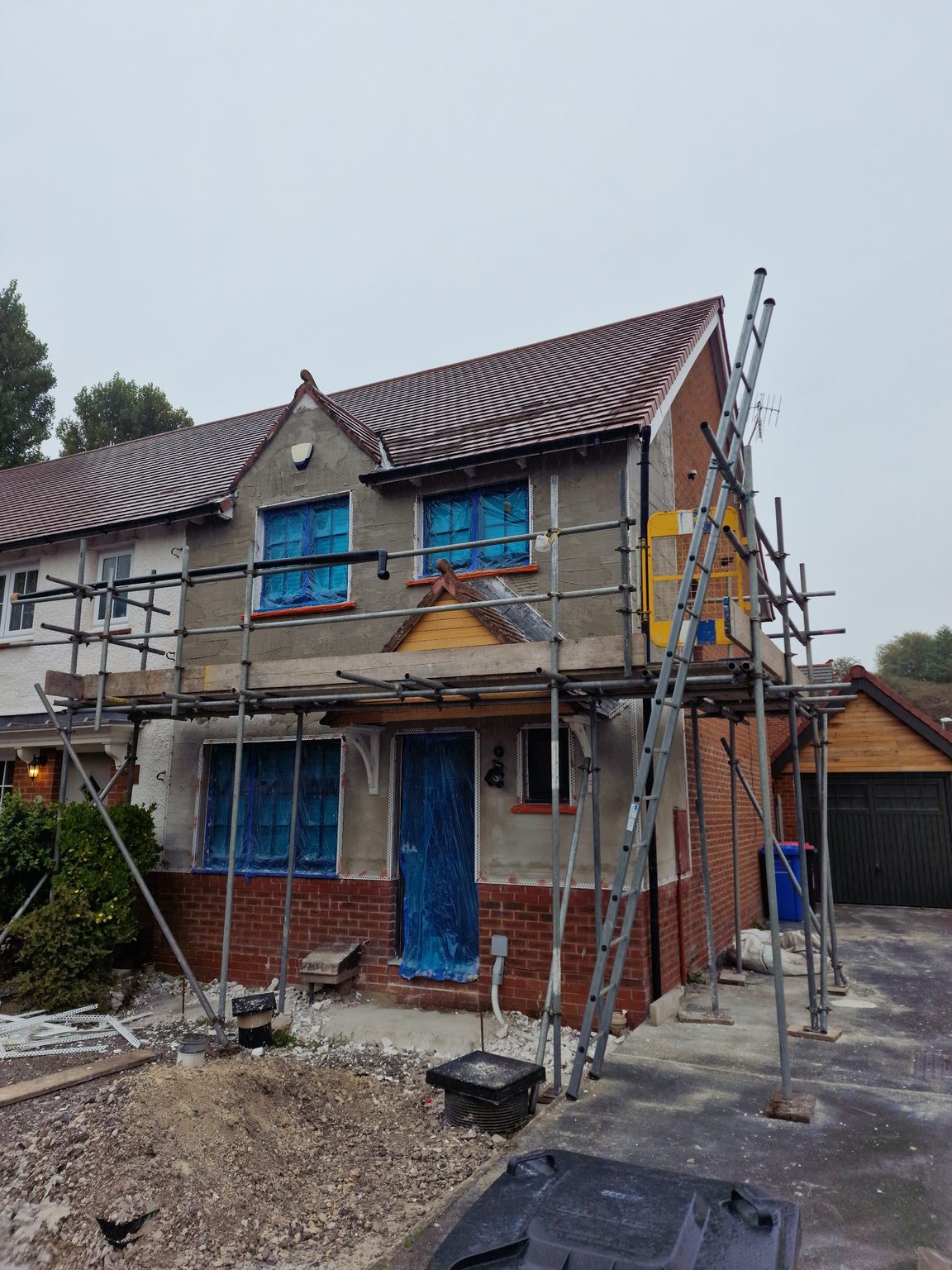 Semi-detached house under scaffolding with windows masked, ready for render